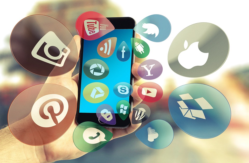Een telefoon met verschillende media logo's die crossmedia aanduiden..